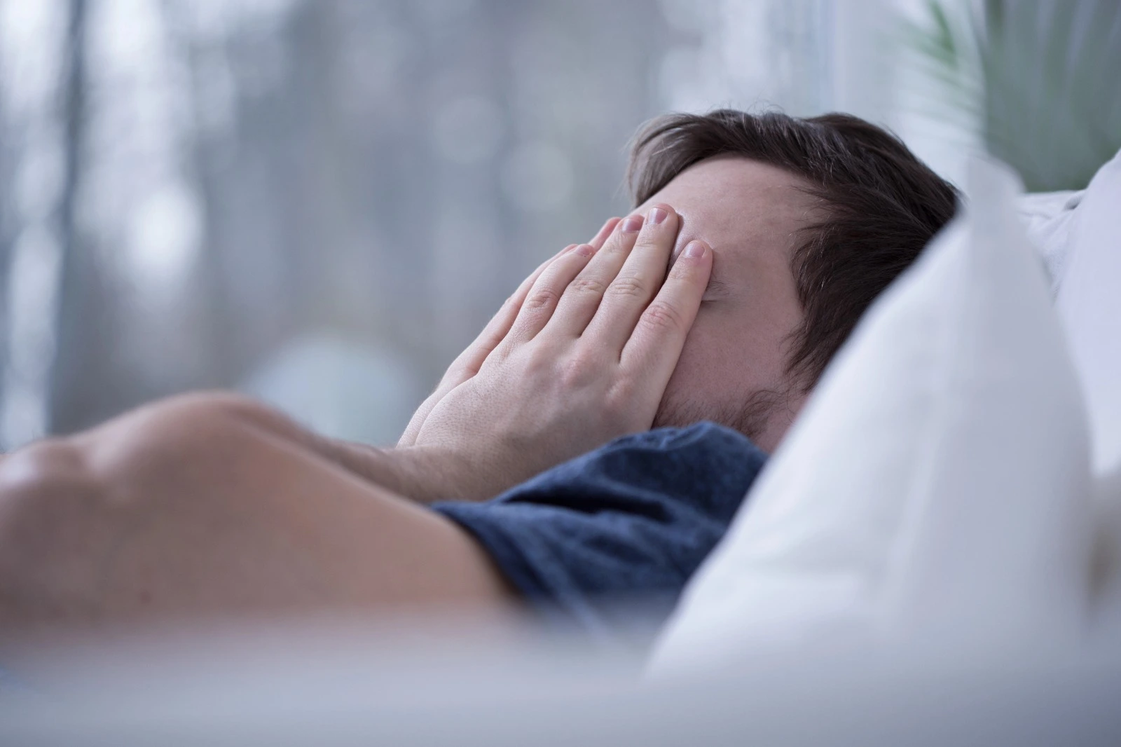 man-in-bed-unable-to-sleep-holding-his-hands-to-his-face