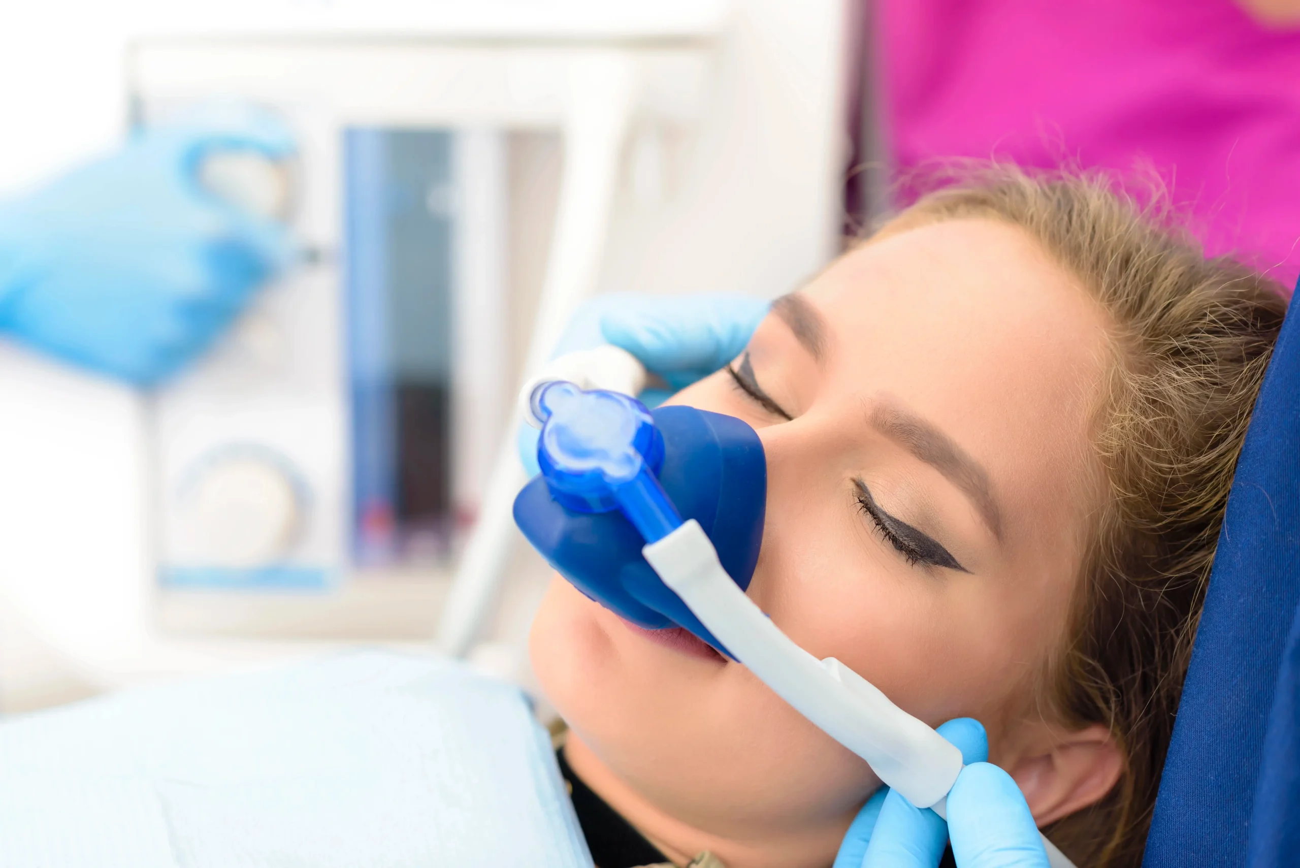 A woman with a blue mask on her face getting general anesthesia before surgery