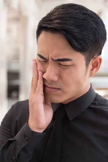 Man holding his face with his hand while wincing in pain