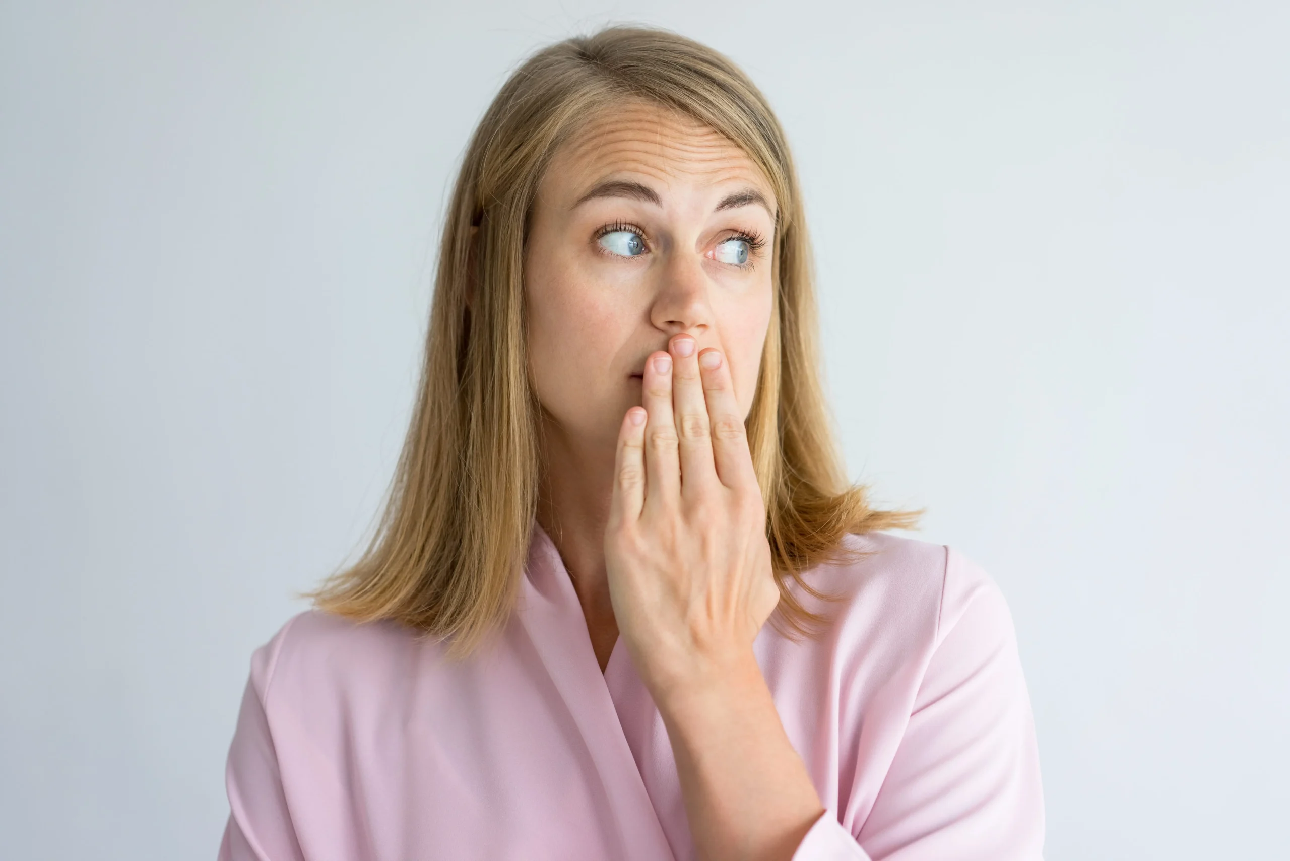 Woman holding her hand to her face trying to smell her breath.