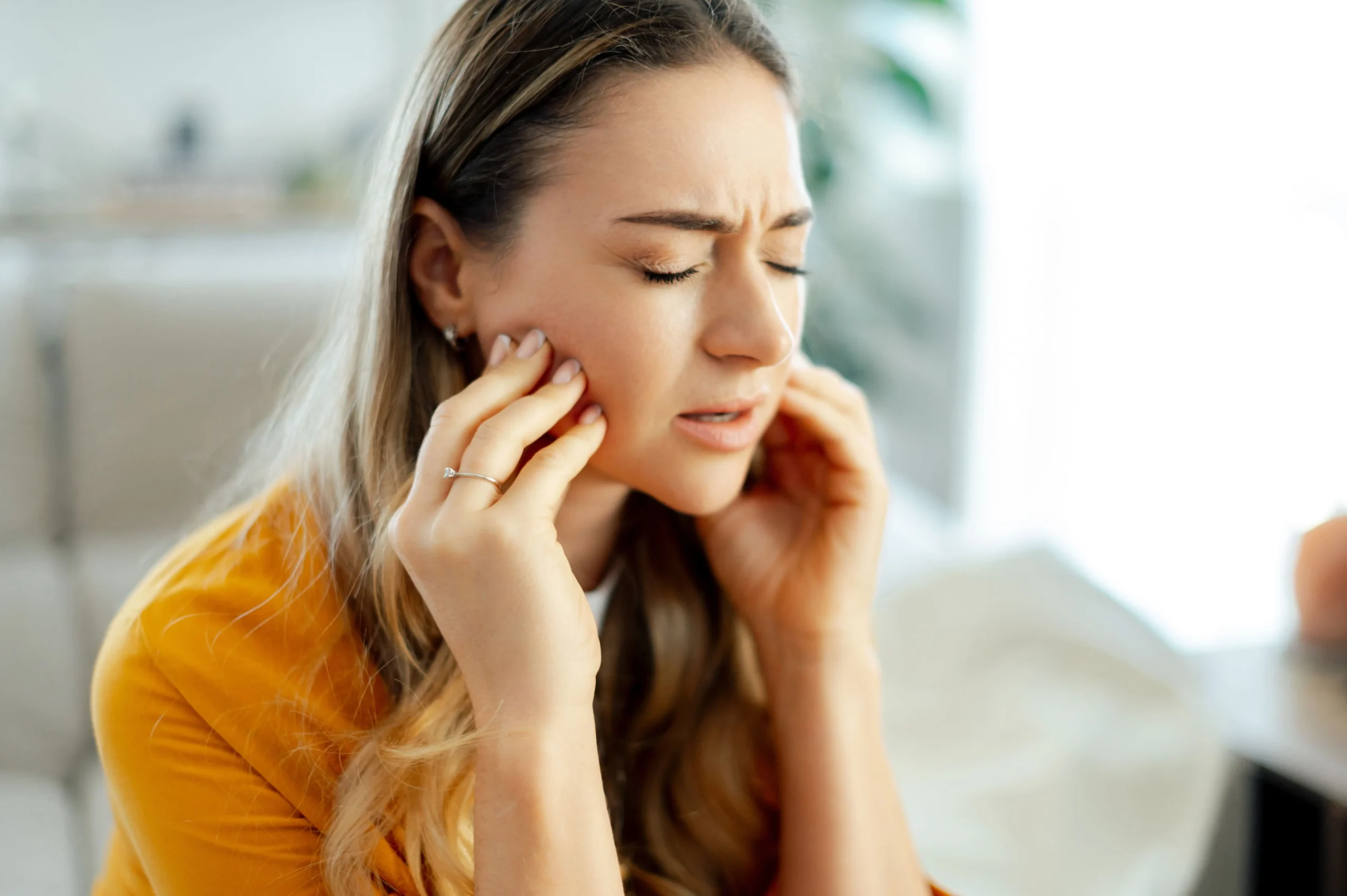 A lady massages her jaw because her wisdom teeth are causing discomfort